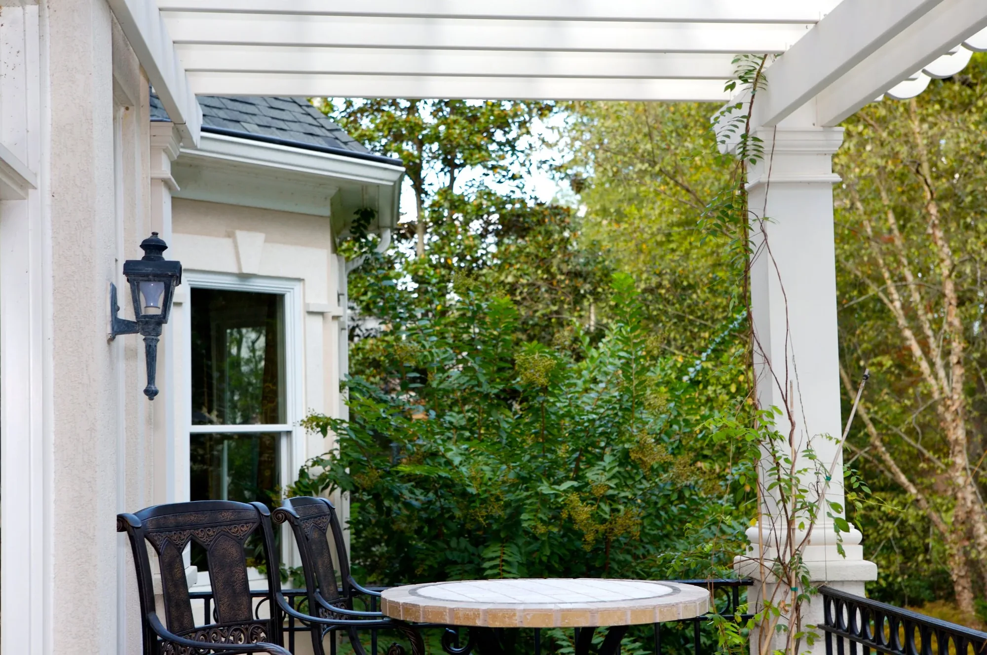 A pergola-covered terrace with a bistro table looking out over the treetops.