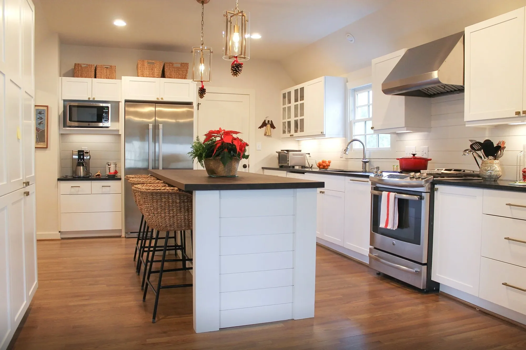 A remodeled kitchen with a large island, white cabinets and a vent hood.