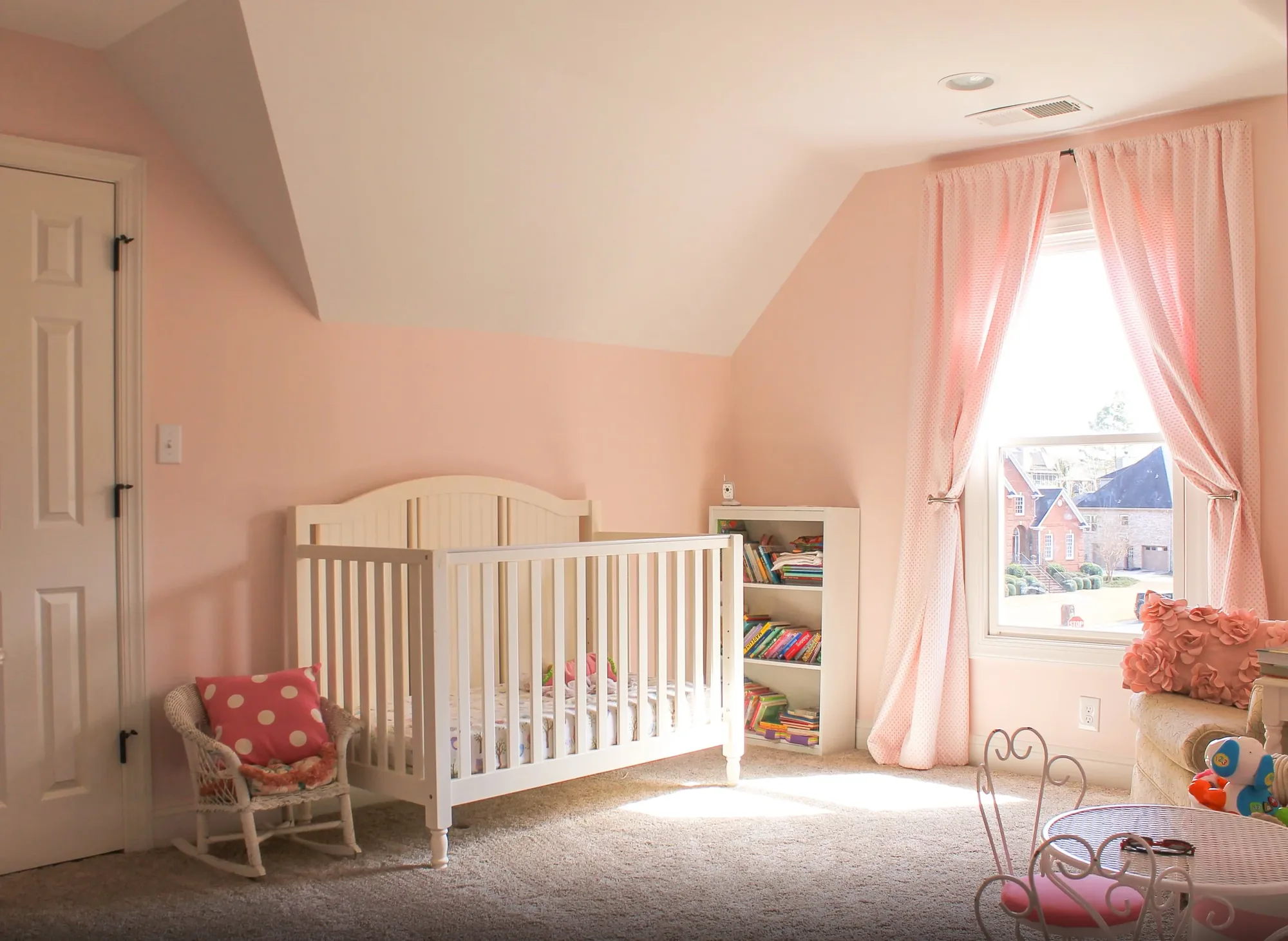 An upstairs nursery under a sloped ceiling with a crib and a dormer window.